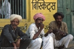 indian men sitting in a street outside a shop